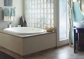 Jetted bath tub with drop-in deck in glass tiled bathroom
